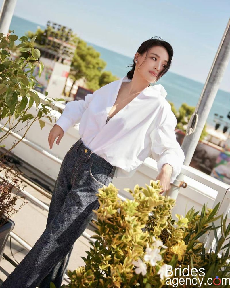 Shu Qi in a white shirt and gray pants